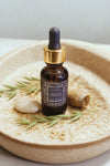 Bottle of True Beauty facial oil on a textured surface with a neutral background